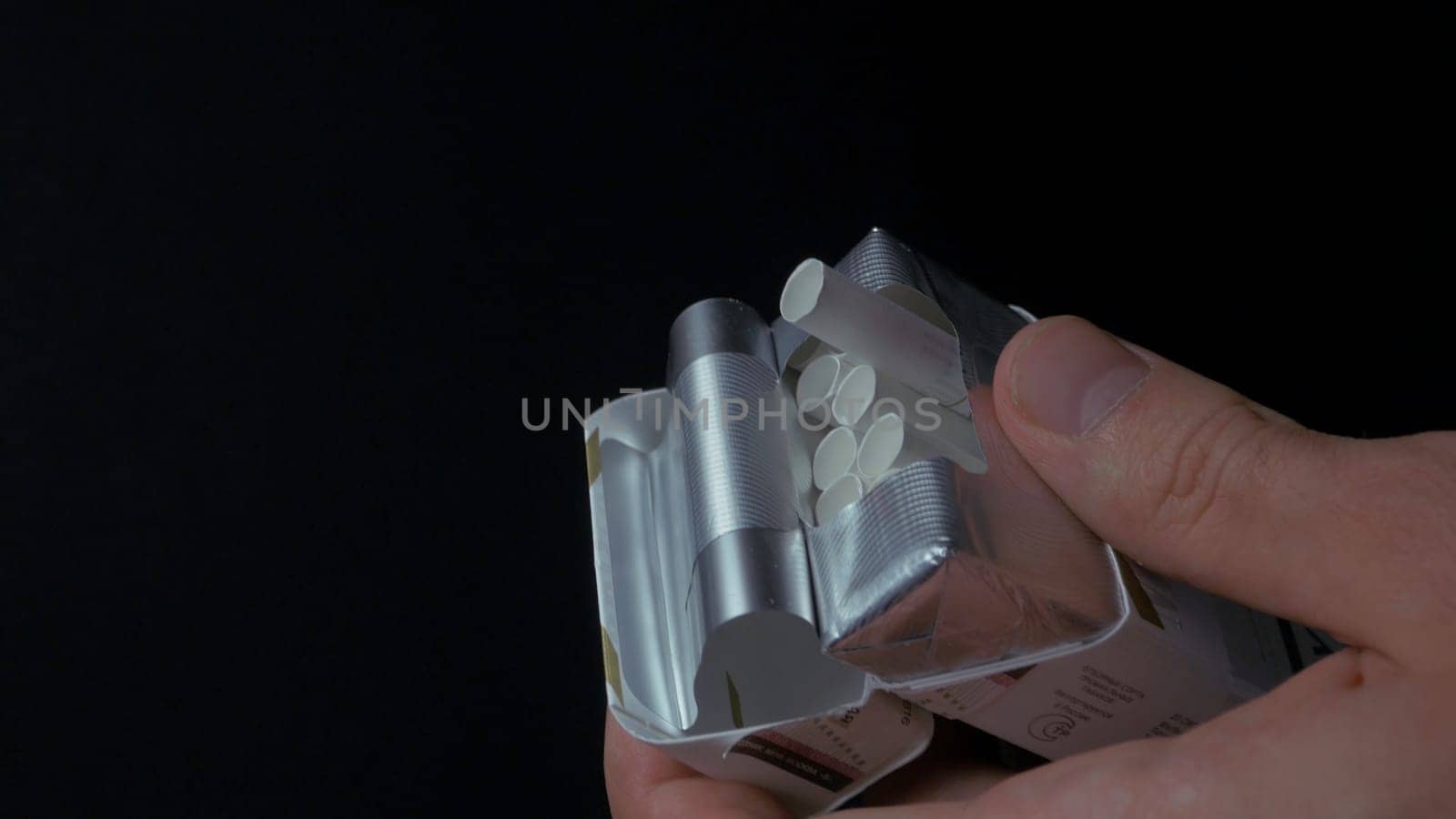 Man's hand pulling up a sigarette from box. Get sigarette from pack closeup. Closeup of a man pulling a nail out of a pack of cigarettes. Box of cigarettes. Hand takes a cigarette out of pack 4K