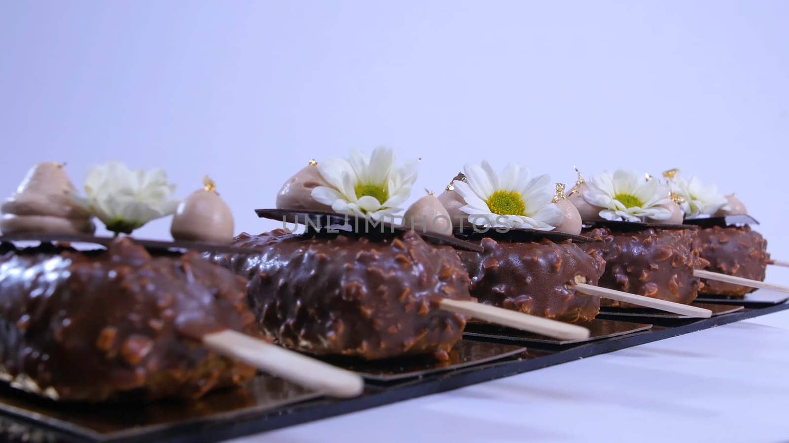 Flowers and cream on the ice cream closeup. hocolate ice cream on a stick. Chocolate ice cream on a stick decorated with flowers.