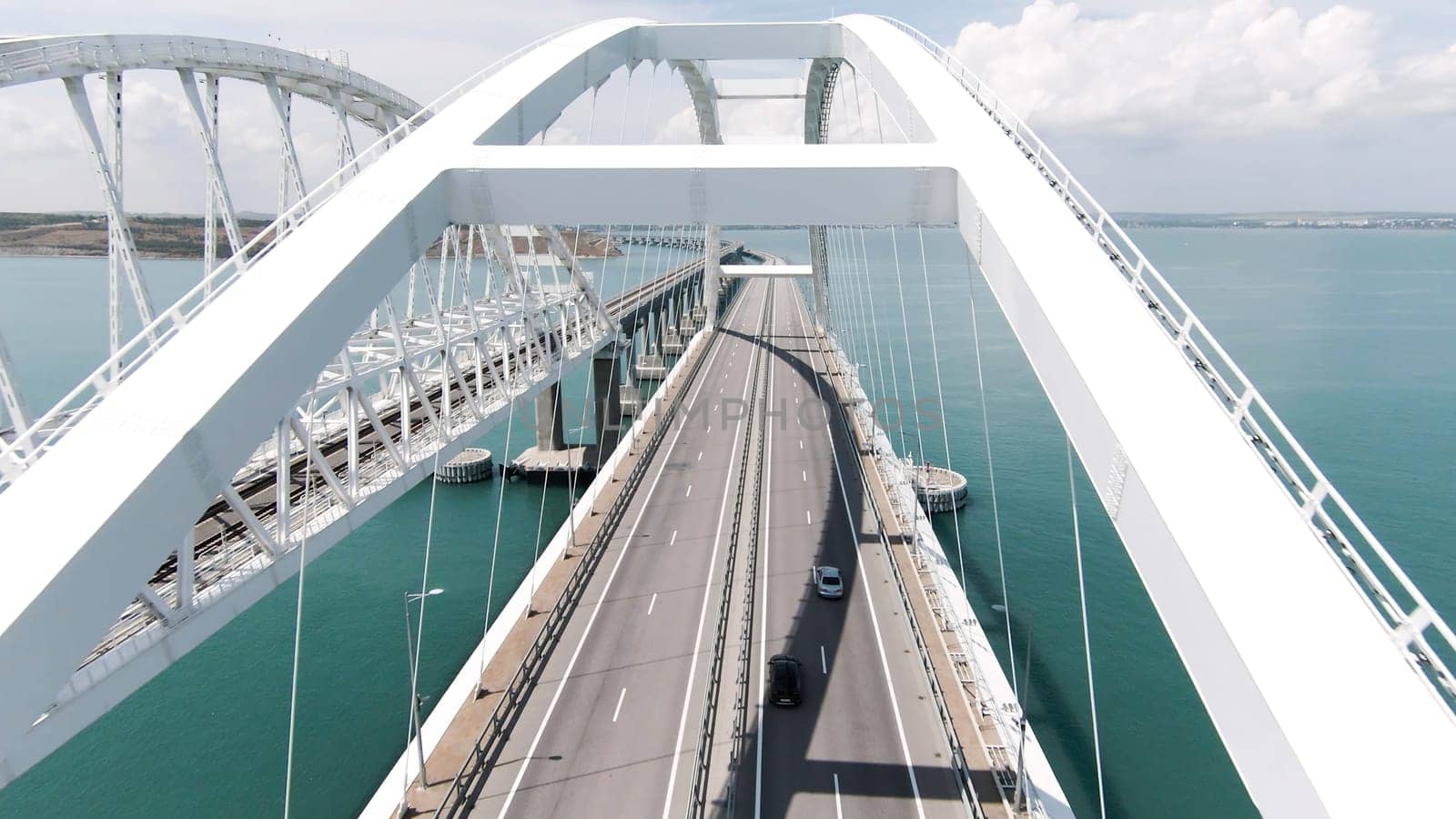Beautiful landscape from a helicopter. Action. The view from the drone on the big white bridge on which cars move over the ocean. High quality 4k footage
