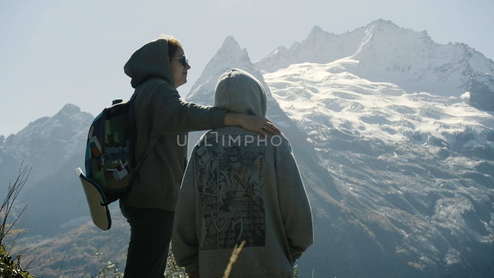 Family walk in the mountains. Creative. A young mother and son climbed to the top of the mountain and enjoy the sunny landscape. by Mediawhalestock