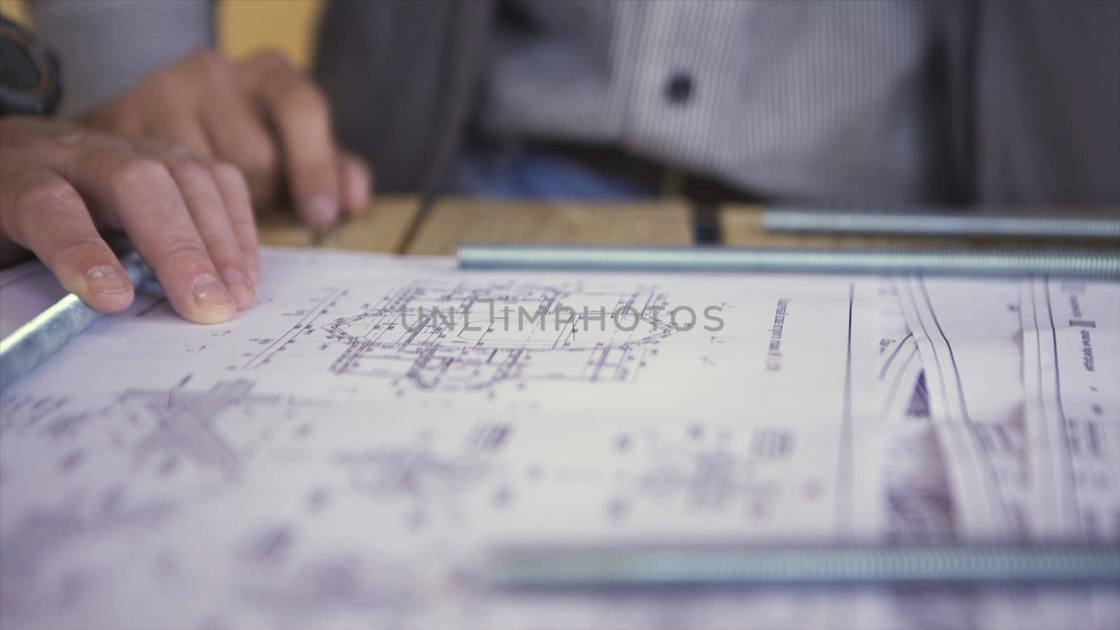 Close up view on engineer hand pointing at technical drawings. Men hands indicating some details in papers, blueprints with building project