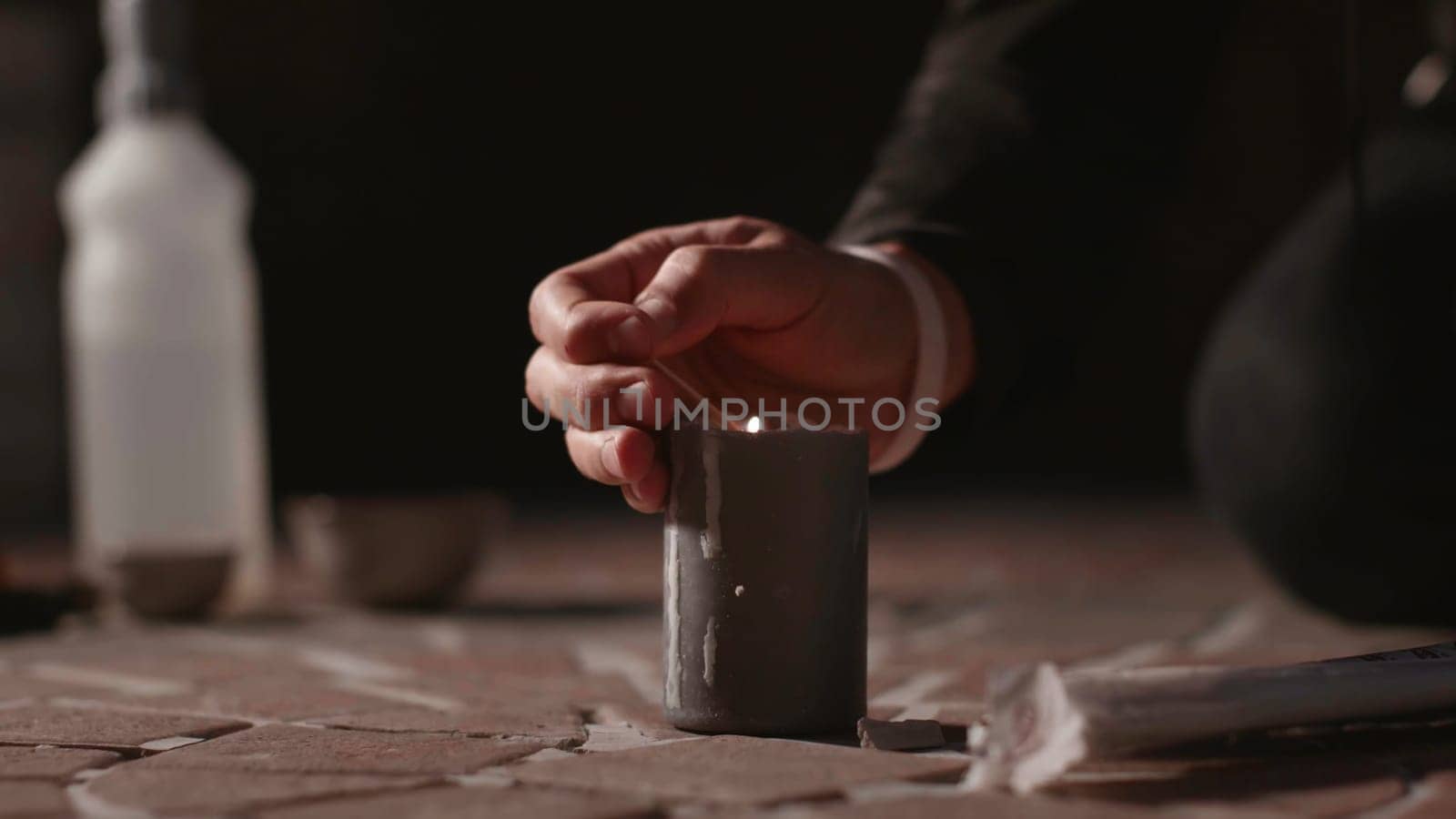 Lighting candle for ceremony. Stock. Man was lighting candle on ground for ceremony. Man with candle at satanic rite.