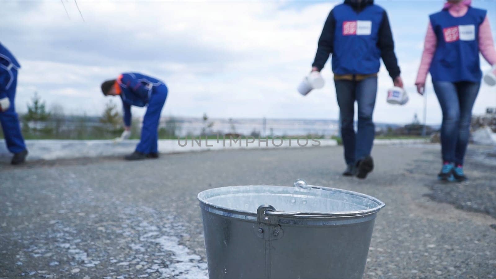 Workers in blue are ready to work for the city in outdoor. Clip. Closeup of a worker. Workers in blue dip the brush in the paint.