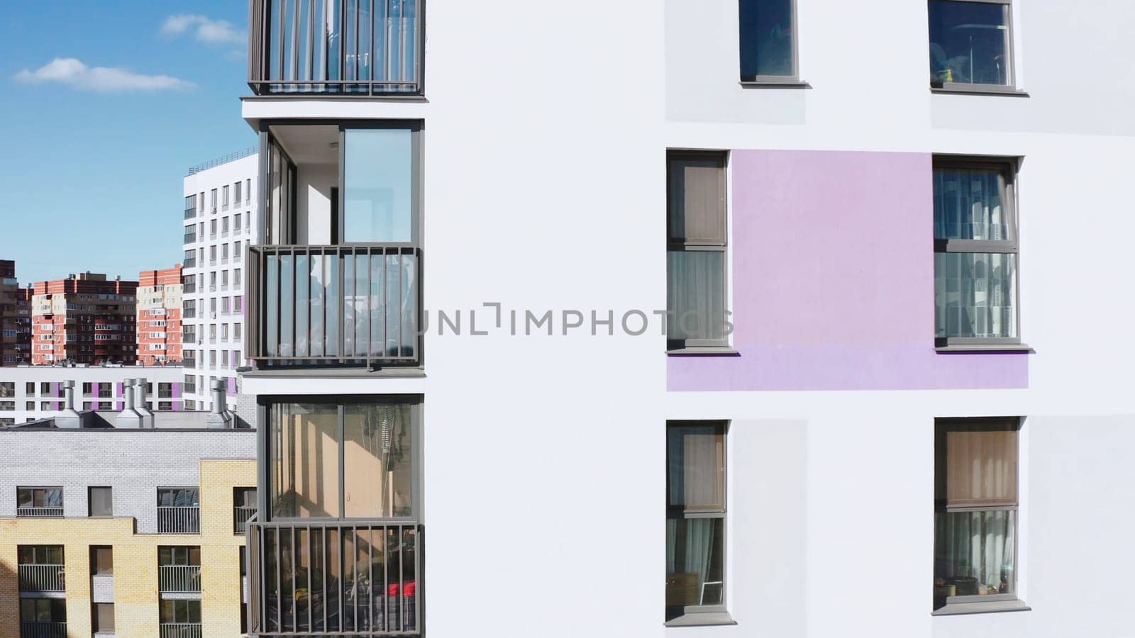Panoramic view of facade of residential building. Stock footage. View of windows of modern apartment building on sunny day. Beautiful facade with windows of residential building in modern complex.