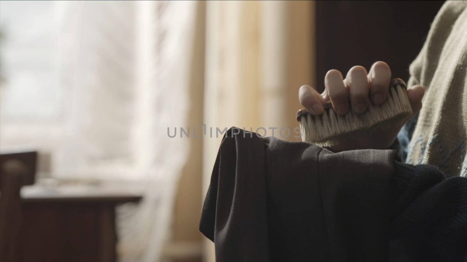 Woman using a lint brush to remove debris from her dress. Woman brushing her pants using a brush close up. Woman's hand using brush to clean clothing