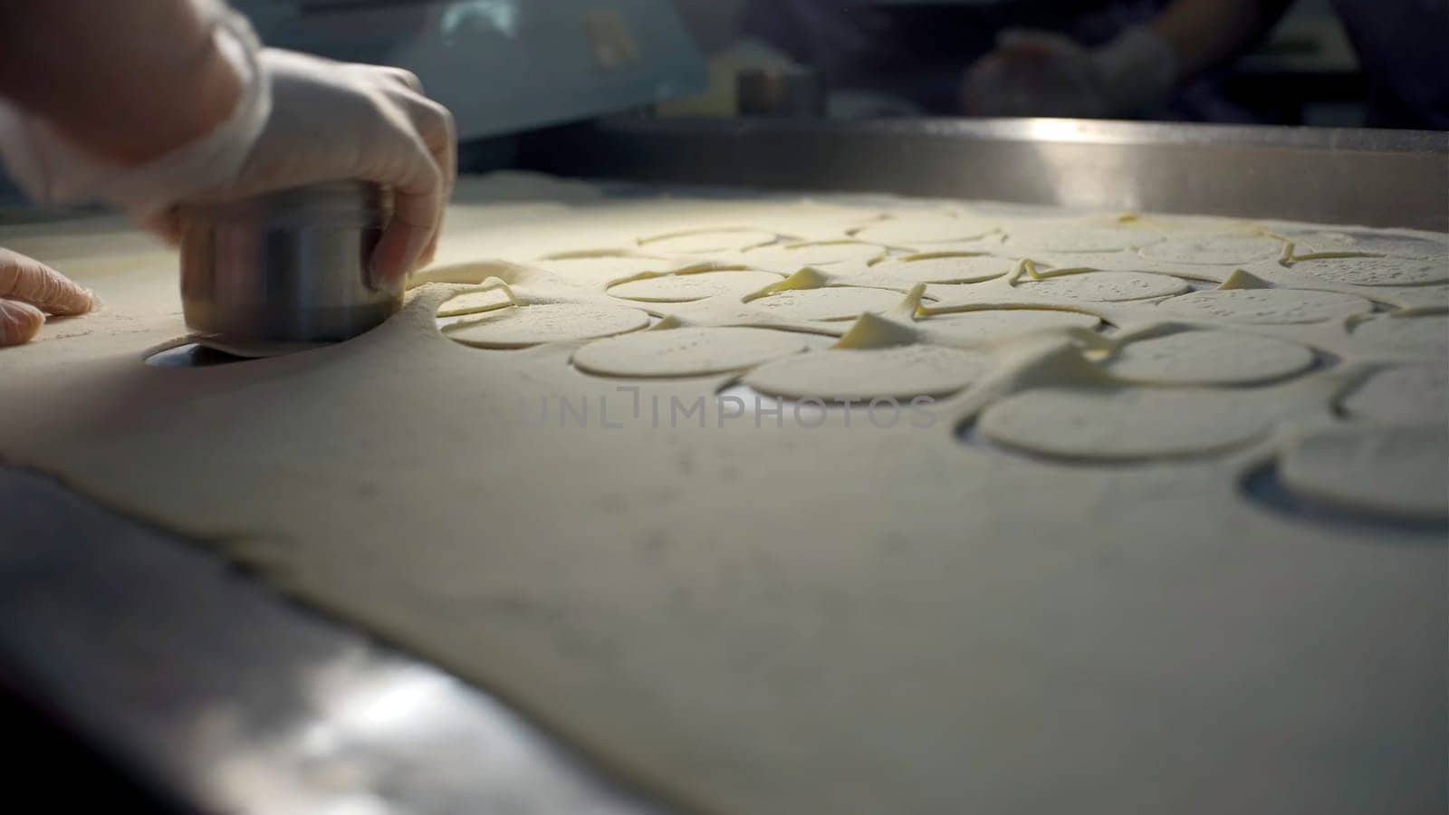 Close up of a hand in glove making flat circles of dough. Clip. Process of dumplings production at the factory