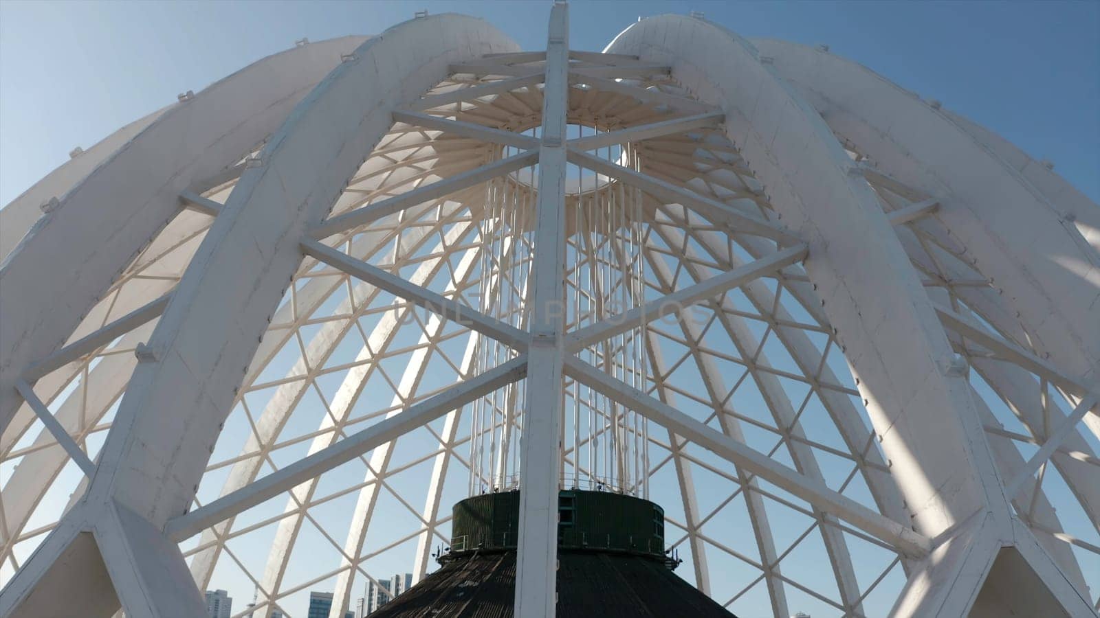 Beautiful domed structure. Stock footage. White air beams in dome structure. Top view of domed circus building on background blue sky.