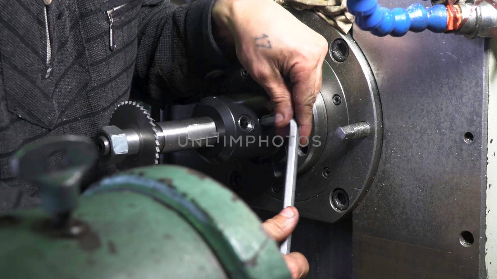 Mechanic repairman at the factory adjusting the machine with large and heavy key, holding it with both hands. Close up of machinery and professional equipment.