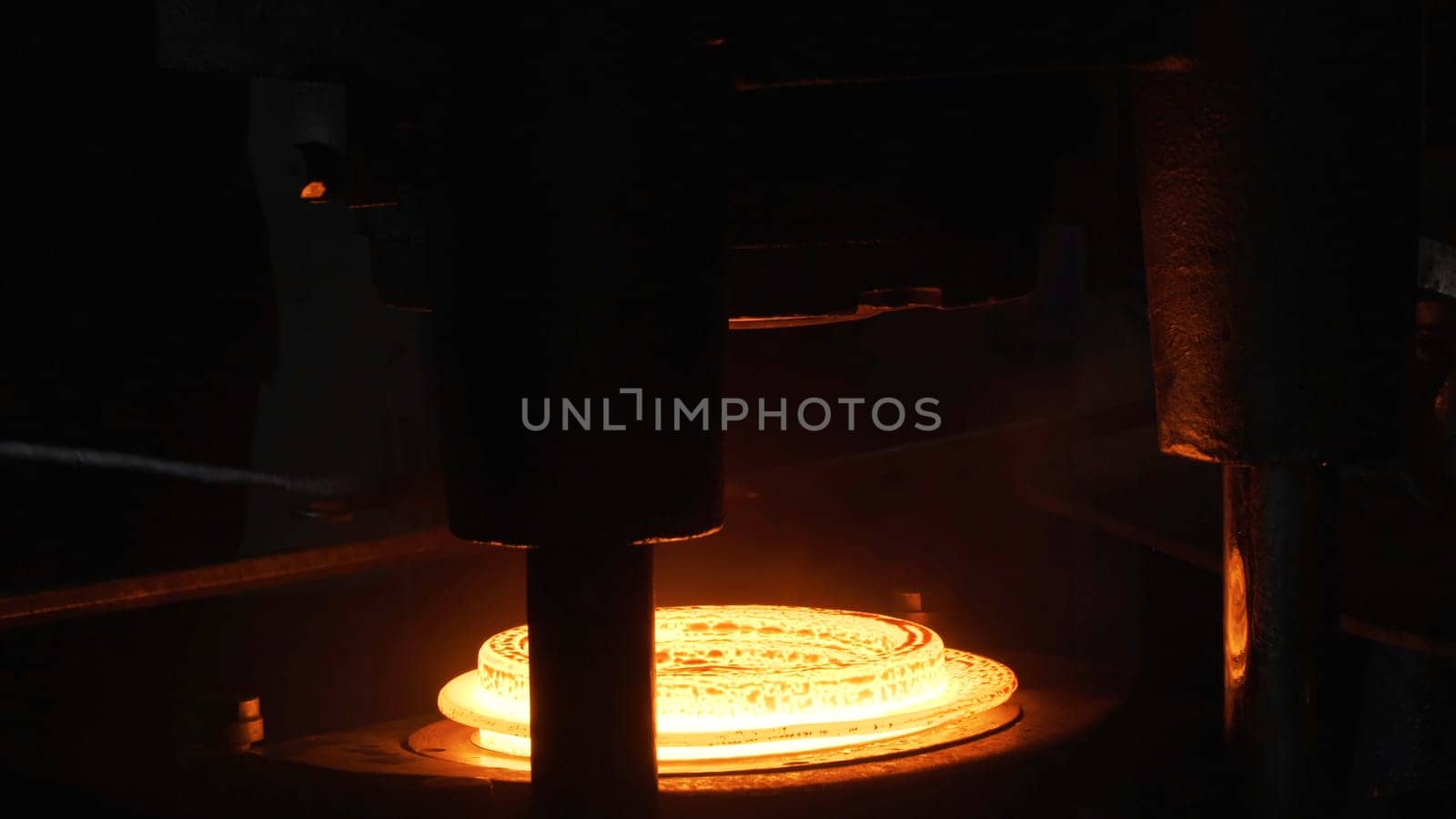 Close up of hydraulic hammer machine shapes the red hot billet at the factiry, heavy metallurgy concept. The production of metal details at the hot shop of the plant.