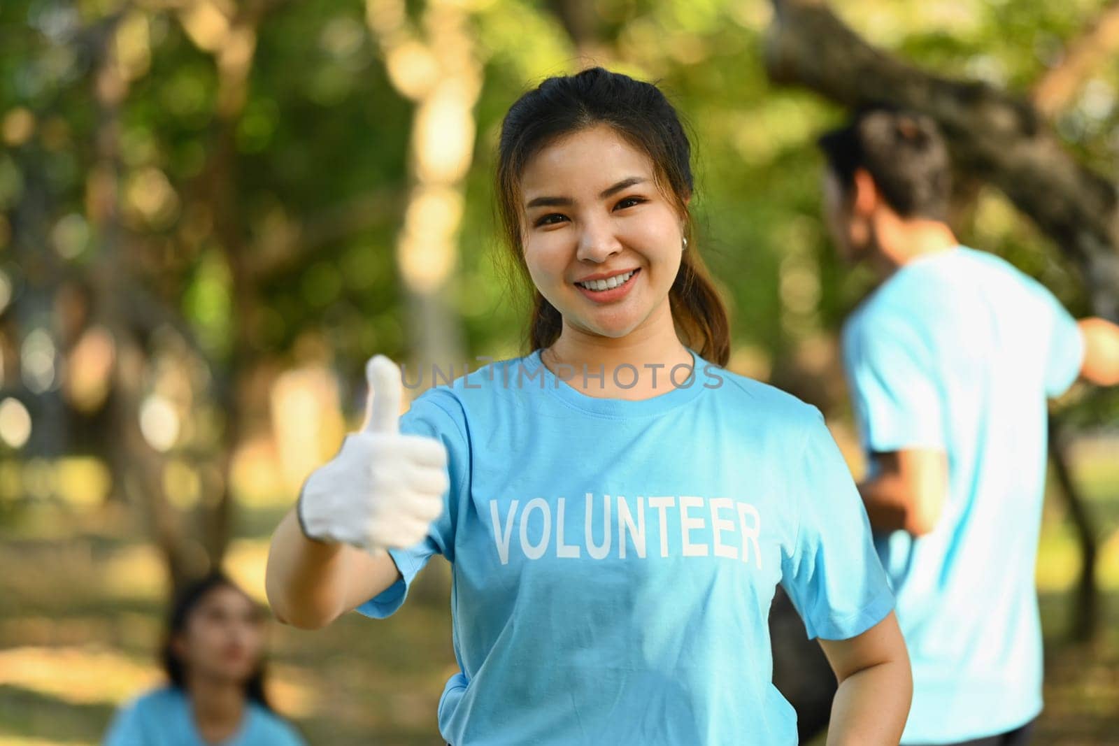 Beautiful Asian female activist in volunteer t-shirt showing thumbs up standing outdoor.