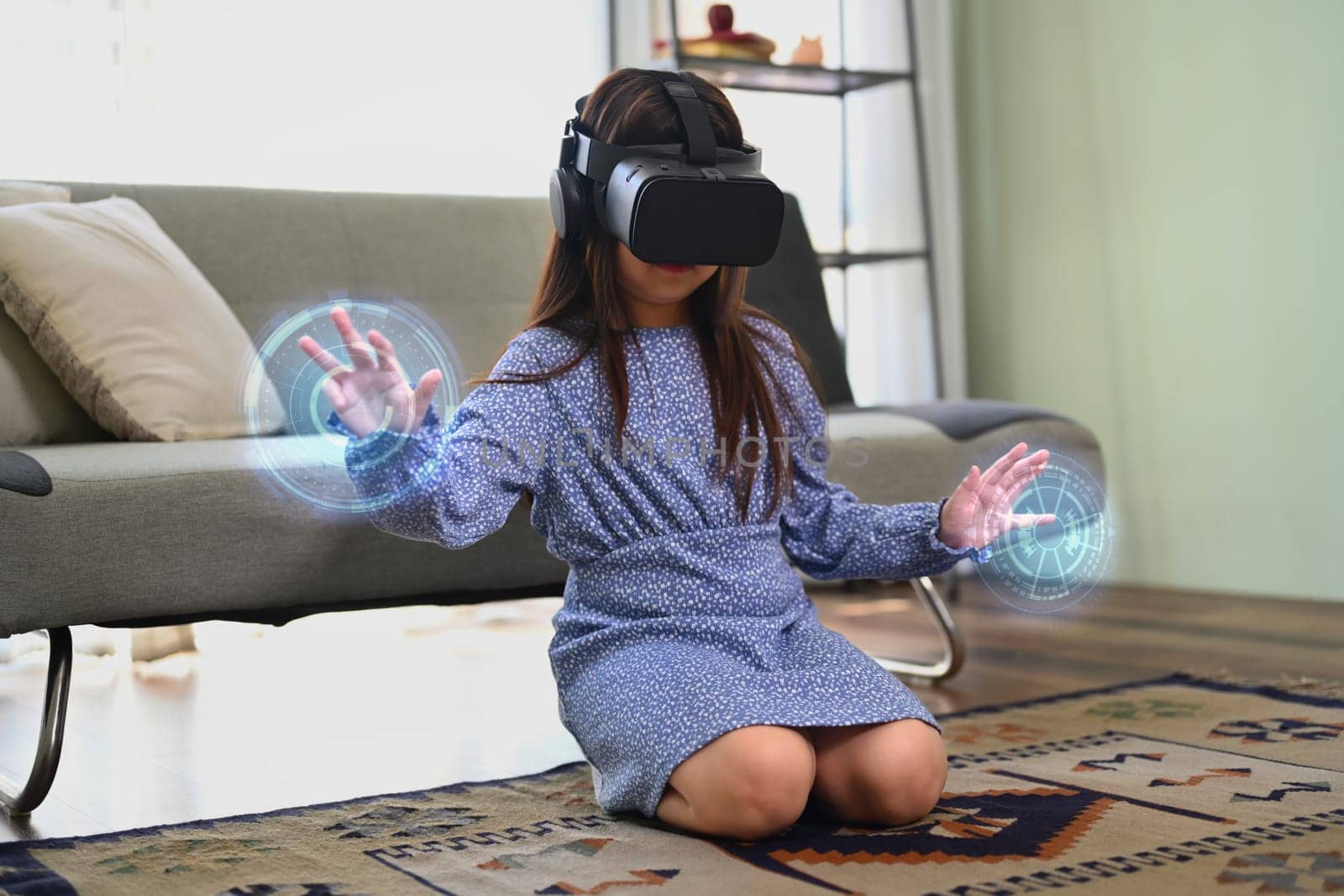 Happy child girl in VR headset touching virtual screen. Concept of futuristic technology. by prathanchorruangsak