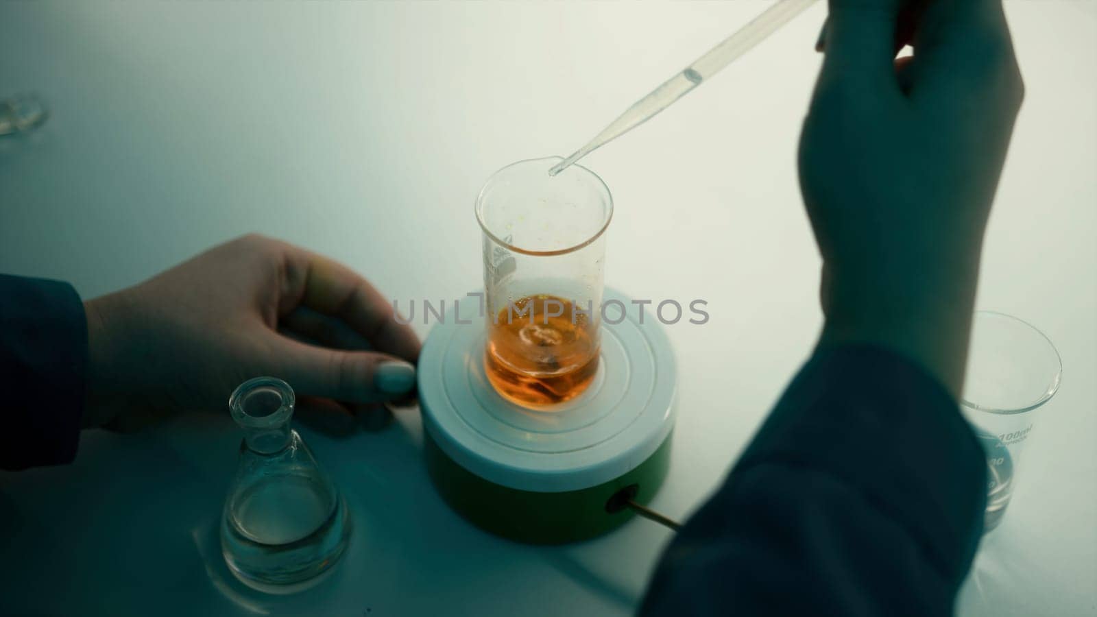 Scientist using a pipette to put solution in glass flask. Stock footage. Concept of medicine and chemistry
