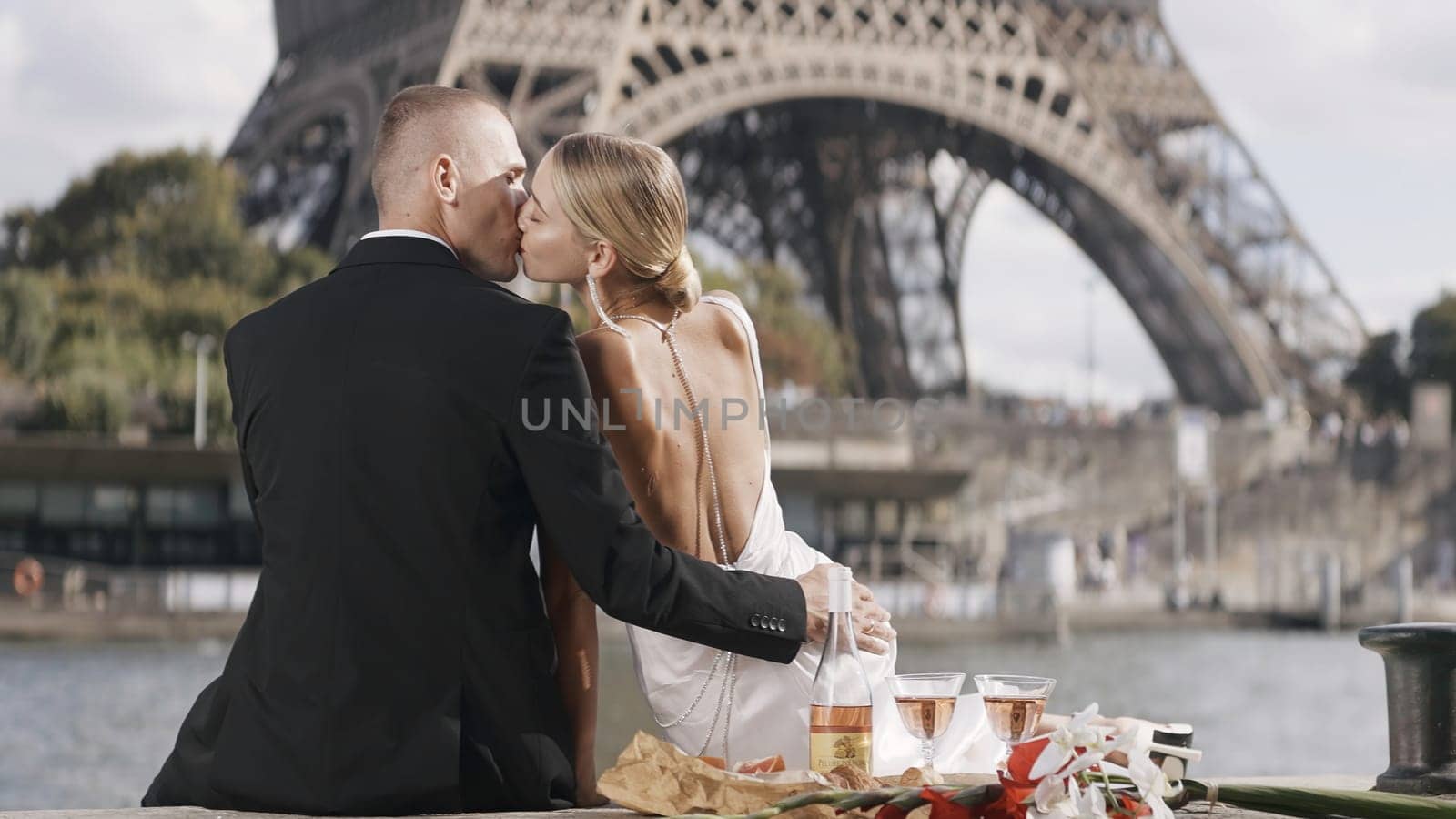 Romantic elegant couple on date at tower. Action. Luxurious elegant couple on date in Paris. Couple on date with view of Eiffel Tower on sunny summer day.