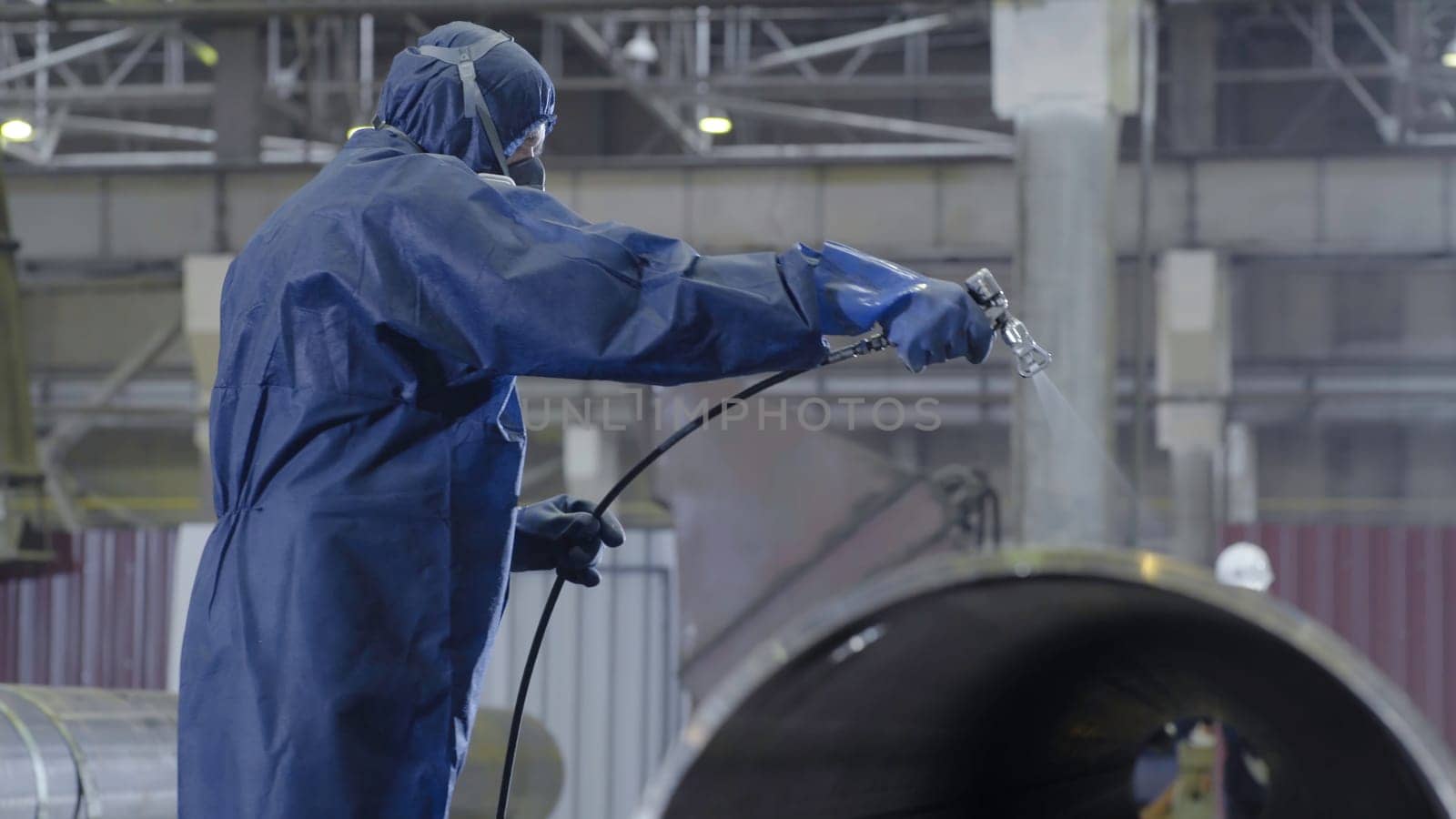 Male holding spray gun and painted steel. Man paints pipe atomizer.