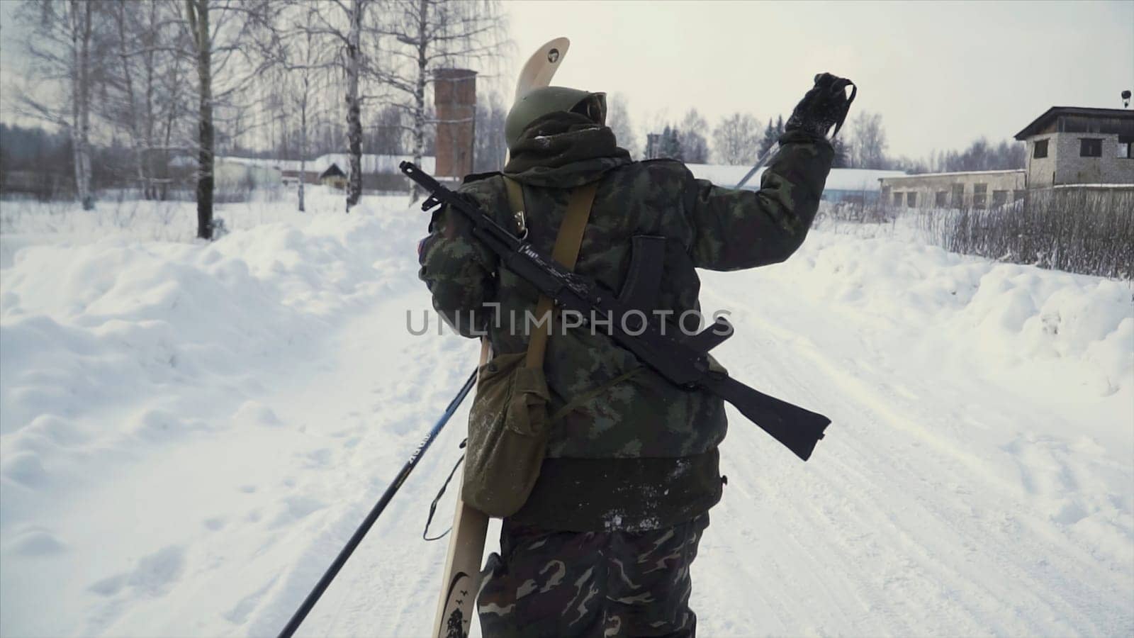 Group of soldiers run on skis in the woods with weapons. Clip. Soldiers with AK-47 rifles and grenade launchers running through the winter forest on skis. Soldiers on exercises in the woods in winter. Winter war and military concept.