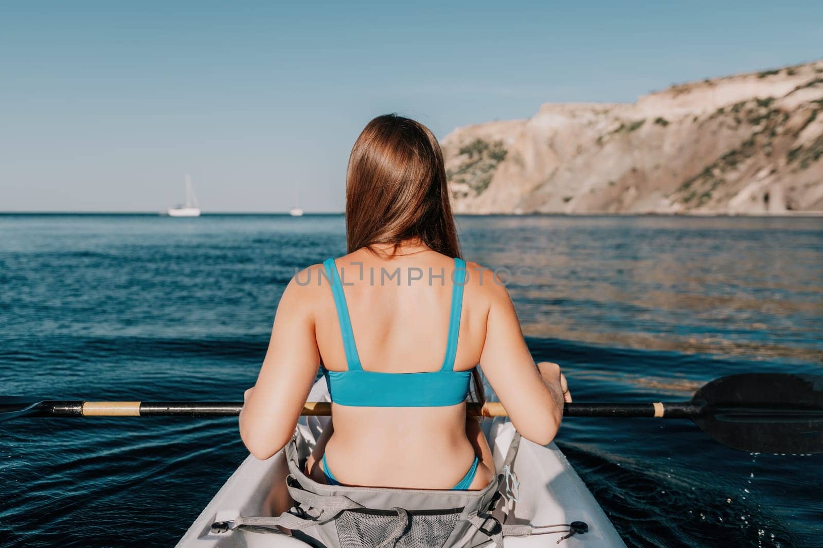 Woman in kayak back view. Happy young woman with long hair floating in kayak on calm sea. Summer holiday vacation and cheerful female people relaxing having fun on the boat. by panophotograph