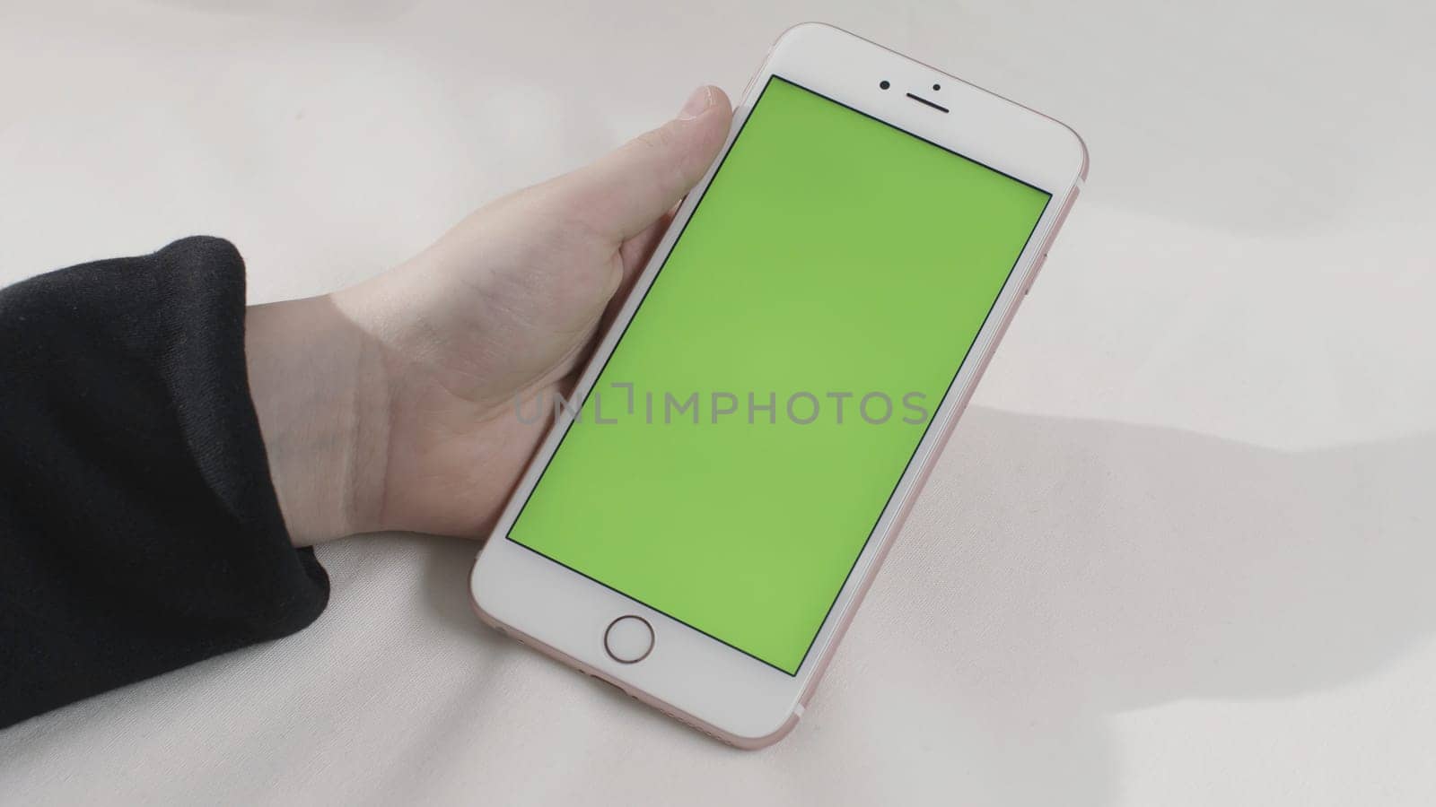 Hand holding touch green screen smart phone on white background. Hand with a cell phone with chroma key.