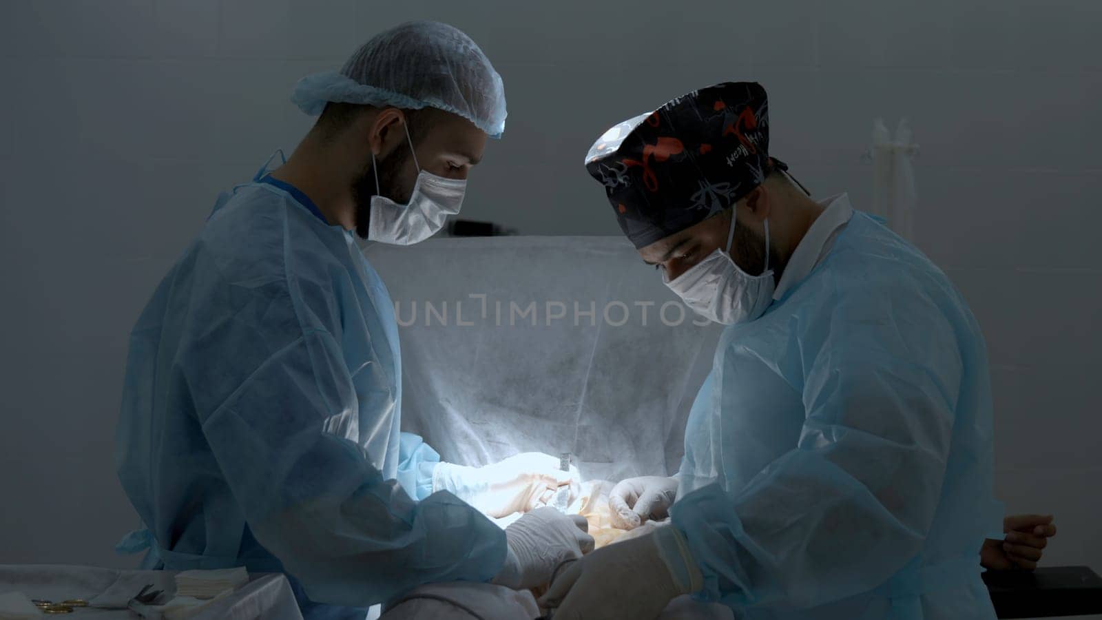 Surgeons working in operating room at a hospital. Action. Two male doctors at work