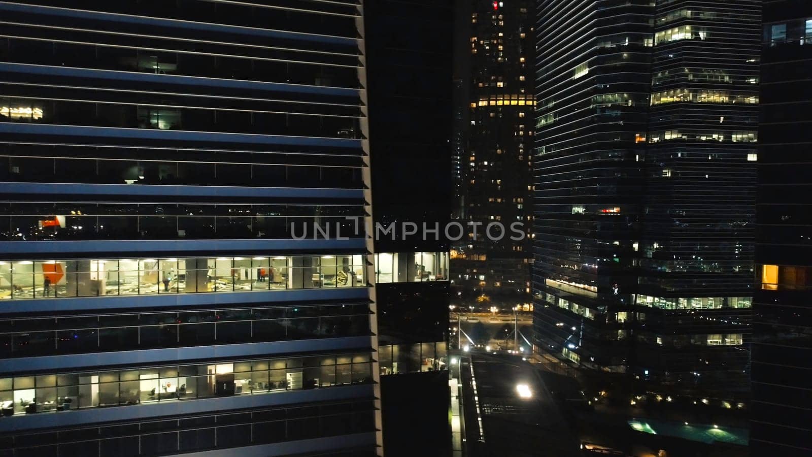 View of a city skyline with skyscrapers in the foreground at night. Shot. Top view of high-rise buildings in center of metropolis at night.