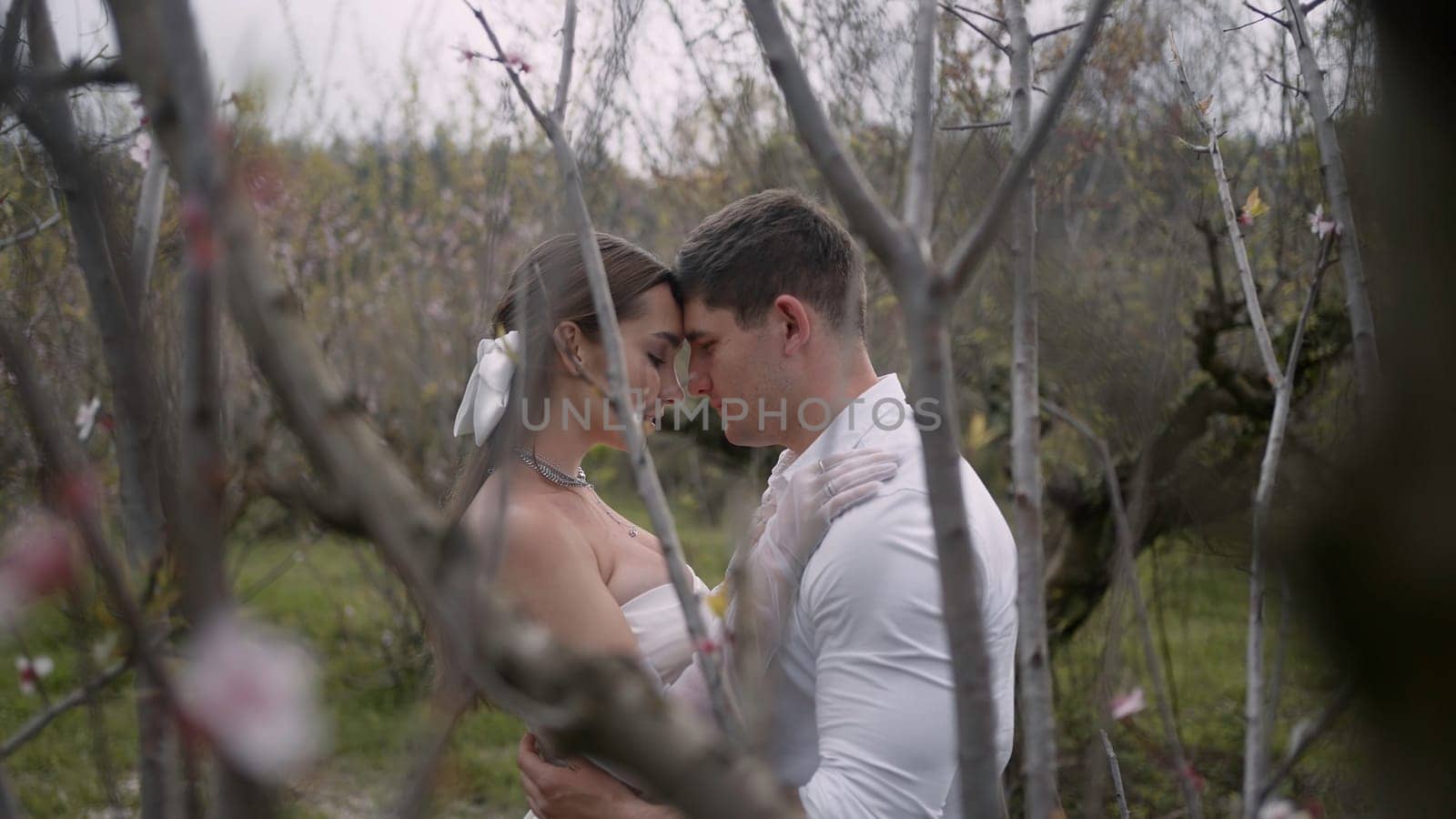 Wedding photosession in a summer green garden. Action. Beautiful bride and groom loving couple posing together outdoors