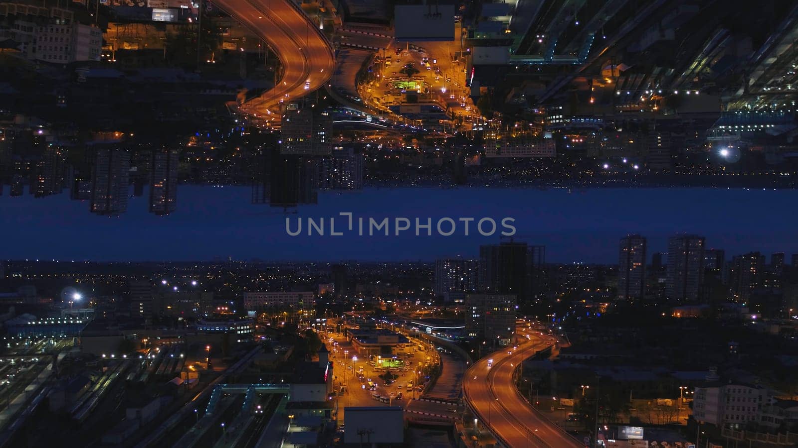 Aerial night view of a big city and beautiful lights, night life concept, mirror horizon effect. Night cityscape with lighted roads and moving cars, inception theme.