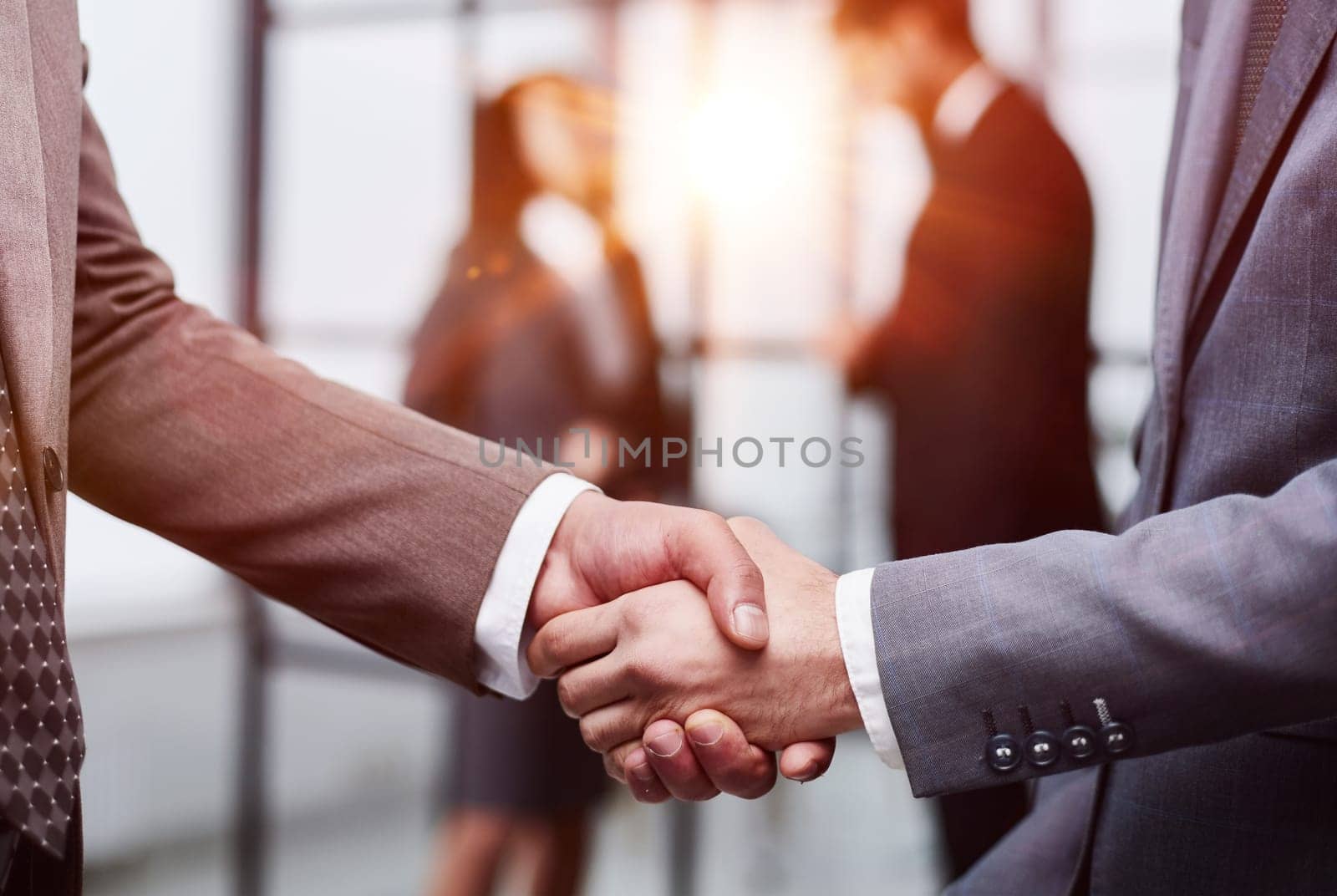close-up of a handshake of business partners against the background of colleagues by Prosto