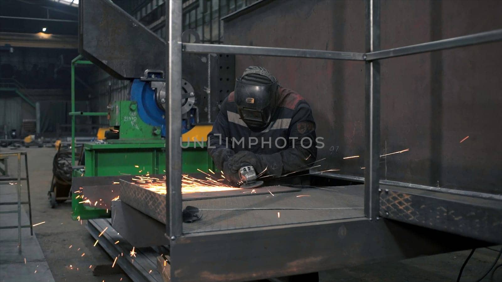Welder grinds plate by welding. Clip. Welder grinds iron plate with sparks. Work of welder in equipment at factory.