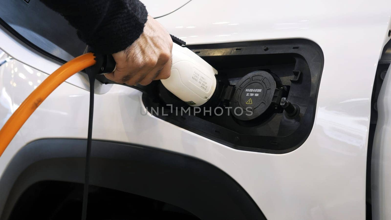 Close-up of charging electric car at station. Media. Electric vehicle charging or refueling station. Modern electric car with charging at station.