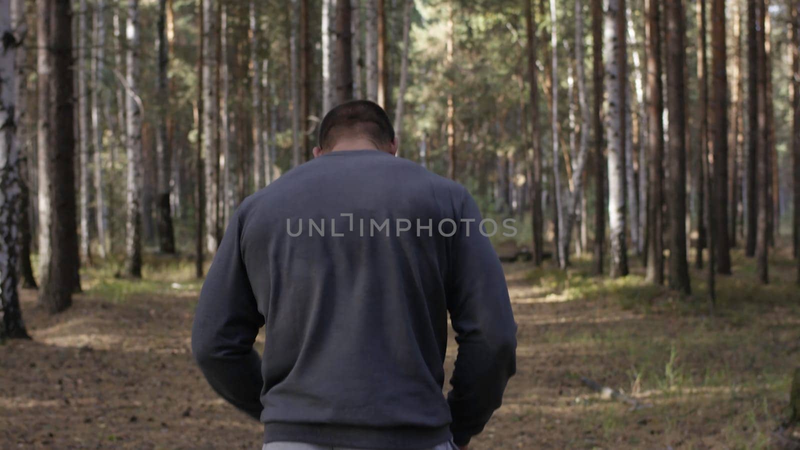 Rear view of fit young man with muscular build standing against sport ground background. Fighter looking at copy space. The muscular male back.