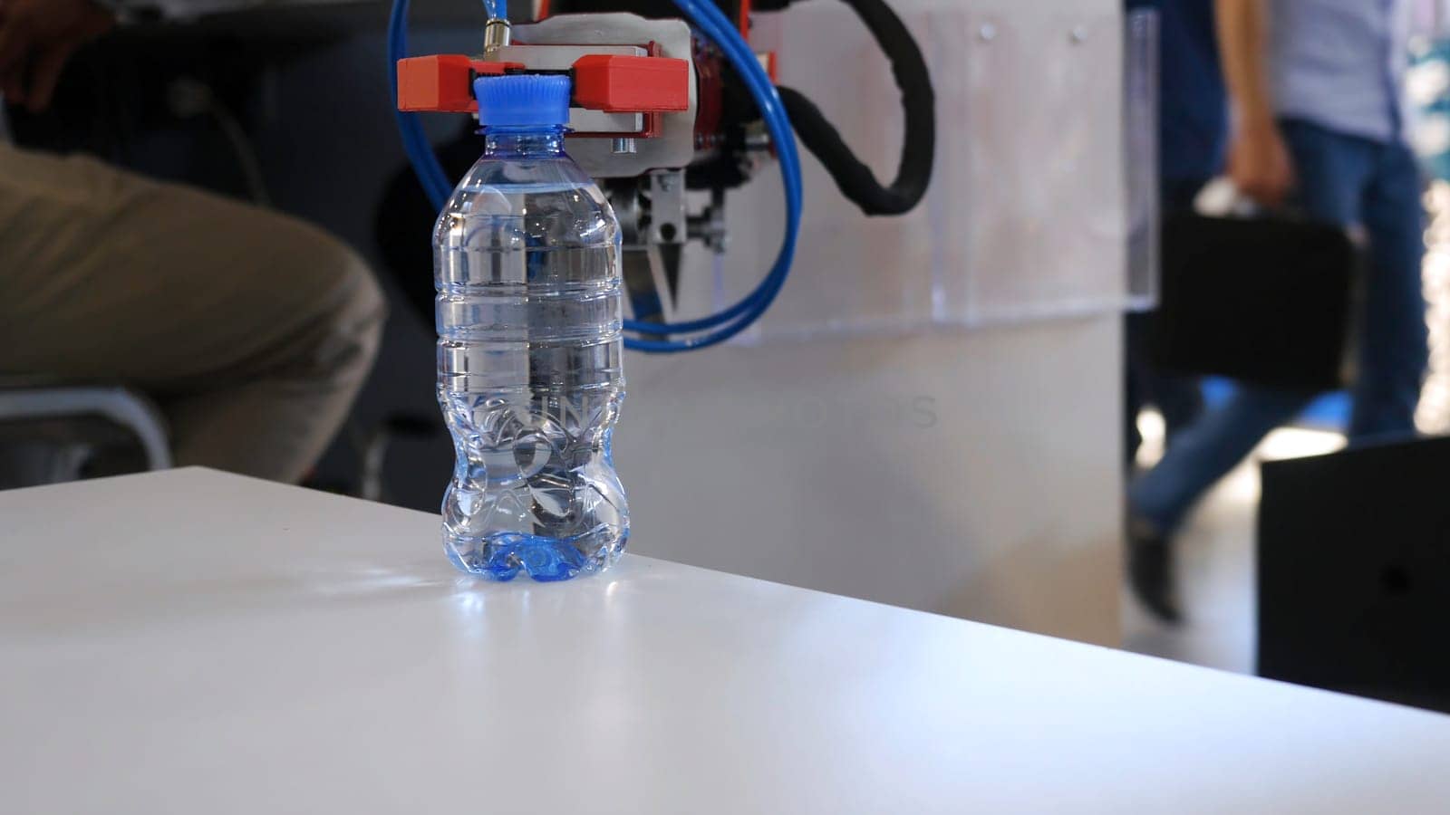 Robot hand is holding a bottle of water. Media. Technological progress. Robotic arm holds a water bottle.