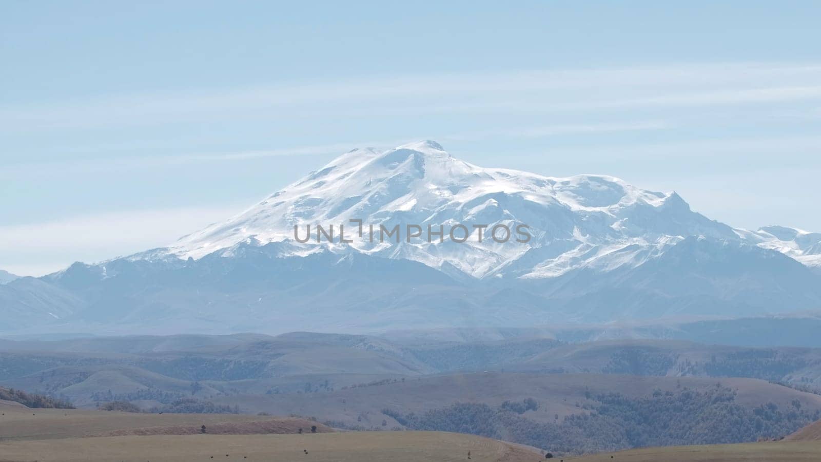 Fog and clouds on rocky snowy mountain background. Creative. Yellow valley at the foot of mountains