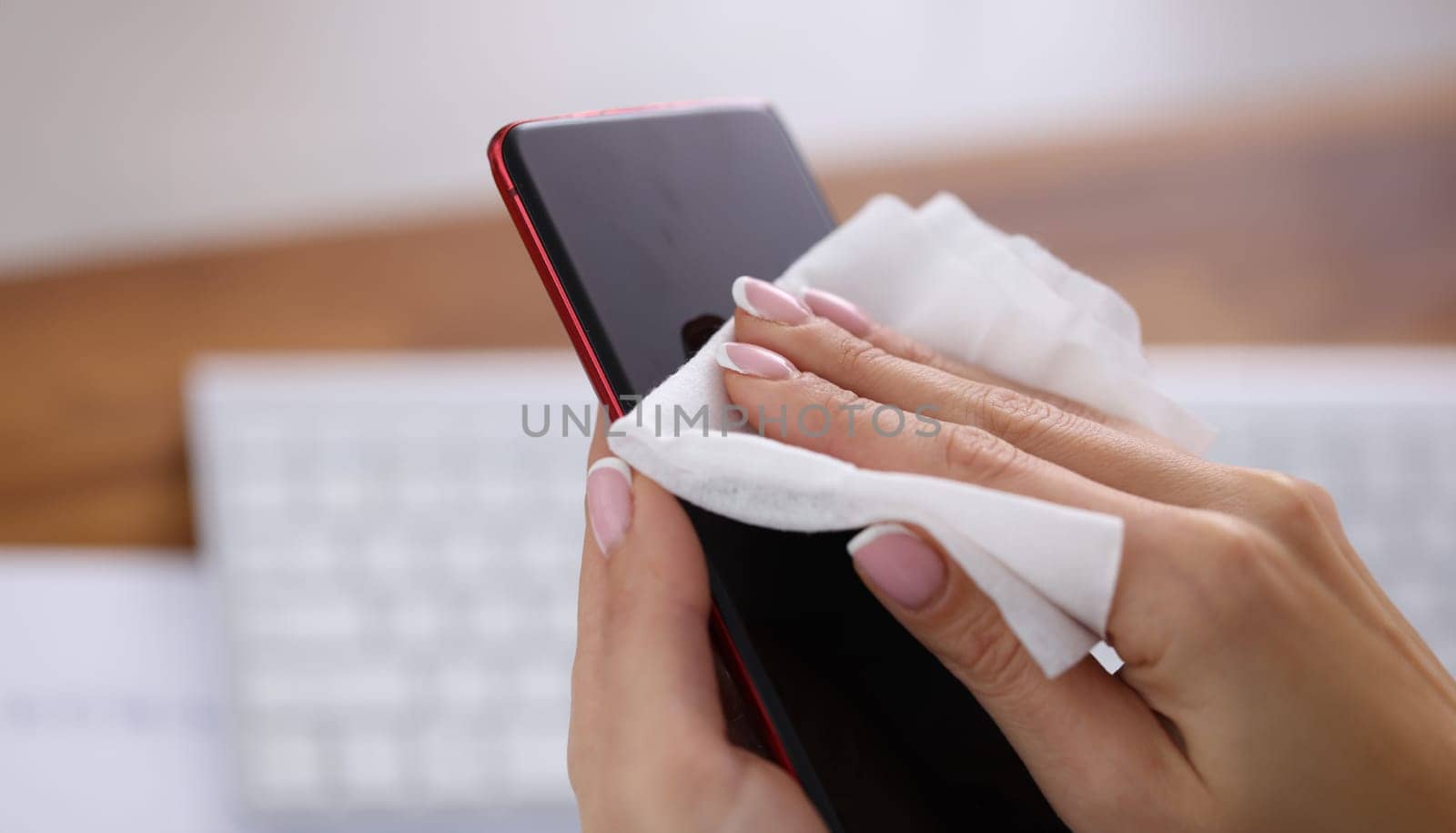 Woman wiping screen of mobile phone with damp cloth closeup. Antiseptic during covid19 pandemic concept