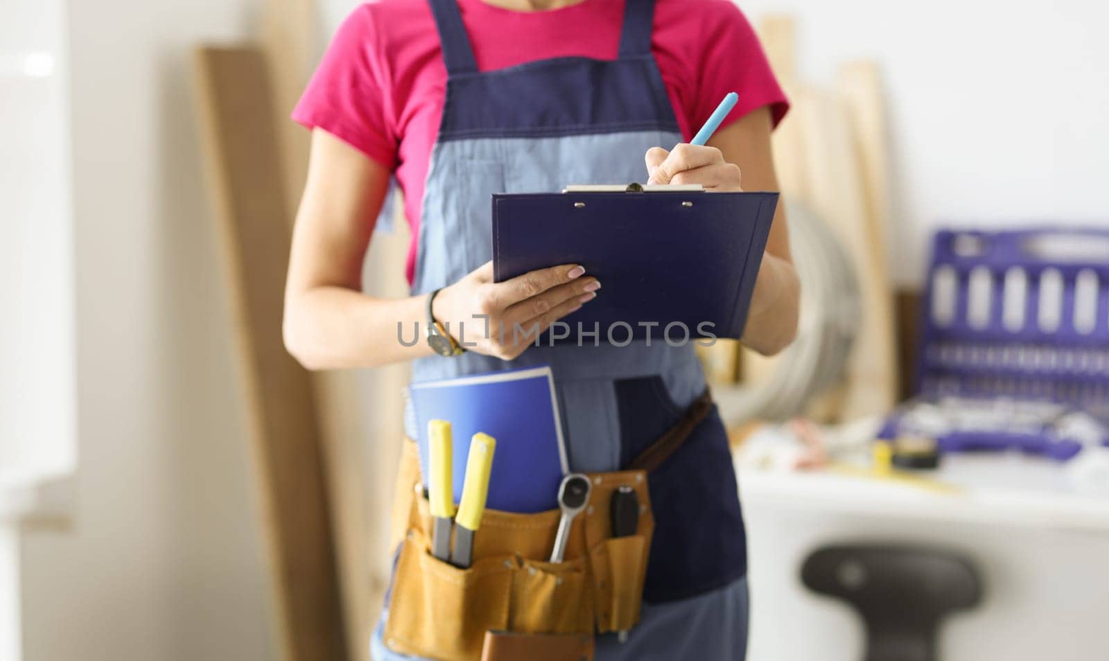 Woman repairman writing paper on clipboard closeup. Quality repair concept