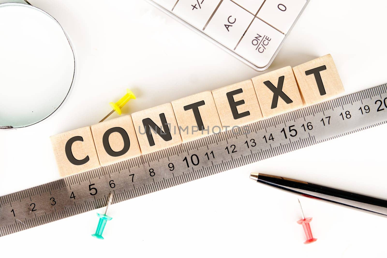 CONTEXT text of non-wooden cubes next to a calculator, pen, measuring ruler, magnifying glass on a white background