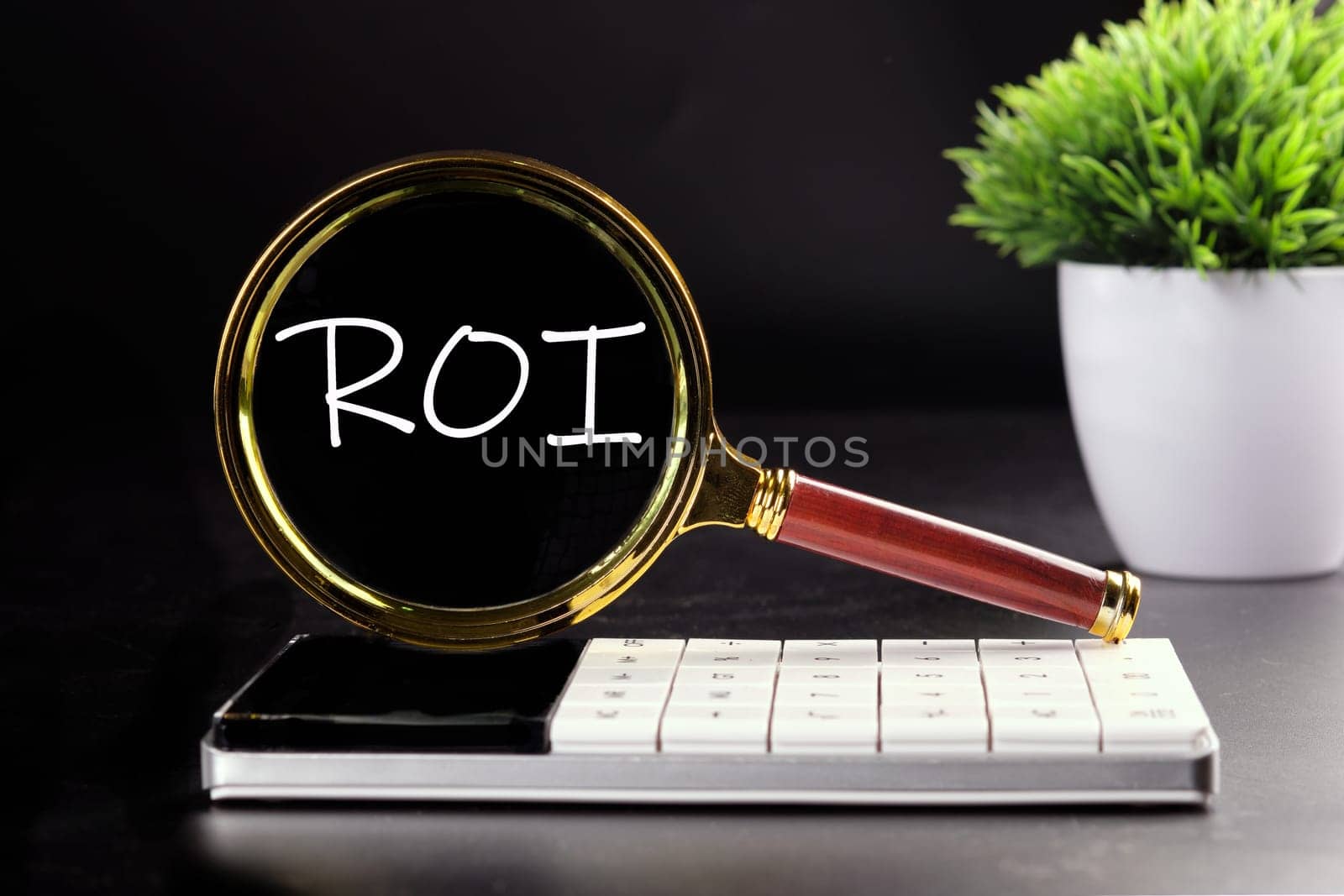 Return on investment concept. ROI text seen with a magnifying glass on a black background