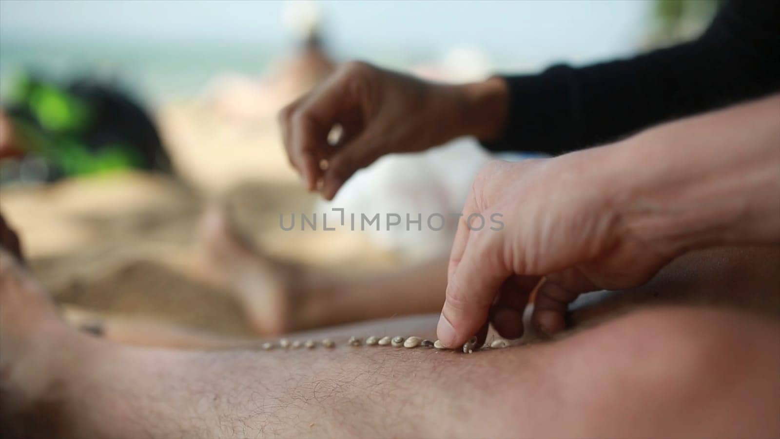 Lazy time. Feet of the man on the beach in the sand on a summer day. Each puts a grain of sand on the foot of the other gays on vacation.