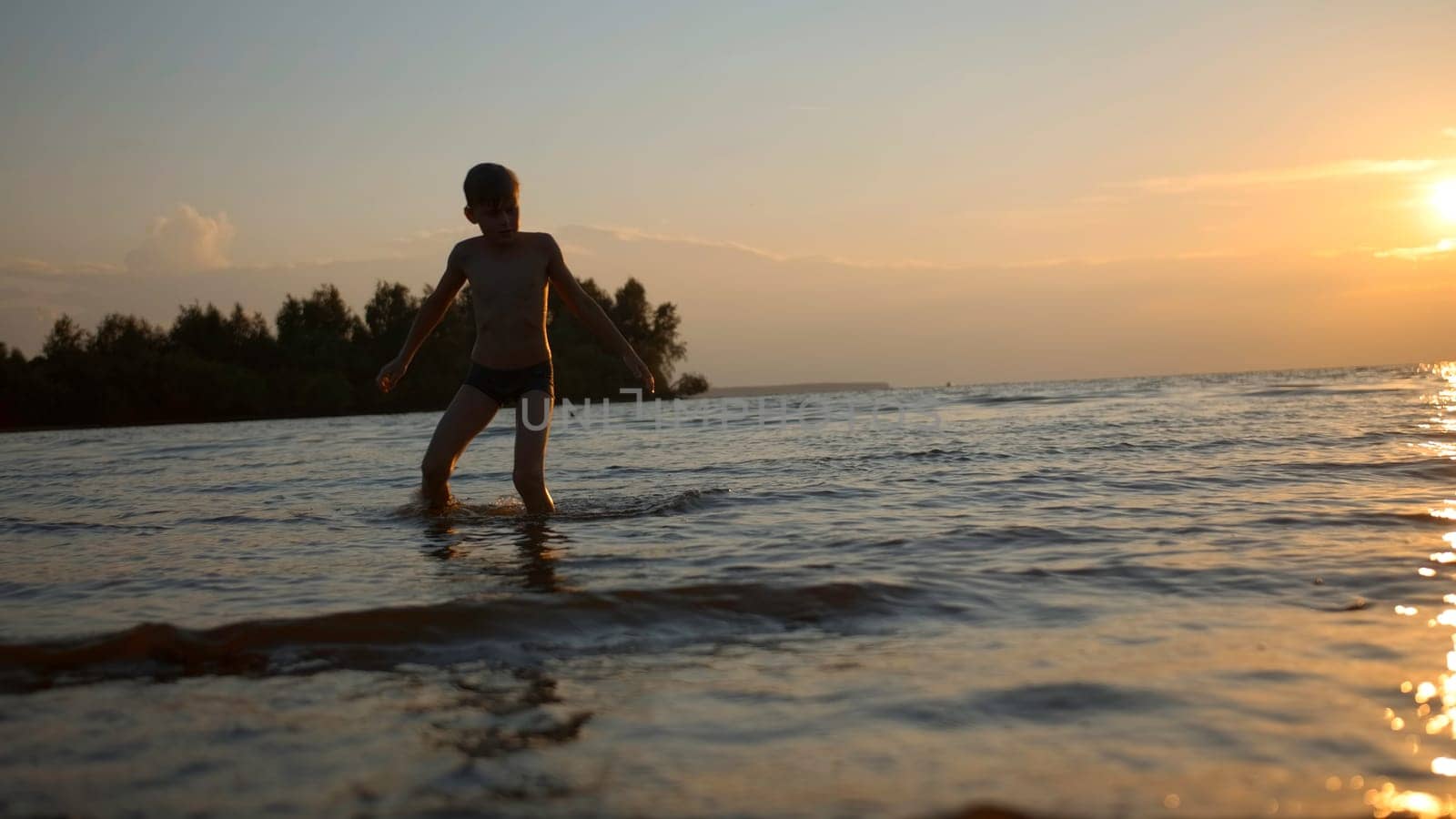 Stunning natural background with sunset above the sea. Creative. Little boy playing in water