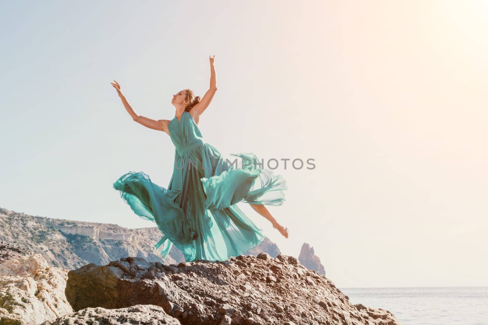 Side view a Young beautiful sensual woman with black hair in a long mint dress posing on a beach with calm sea bokeh lights on sunny day. Girl on the nature on blue sky background. Fashion photo by panophotograph