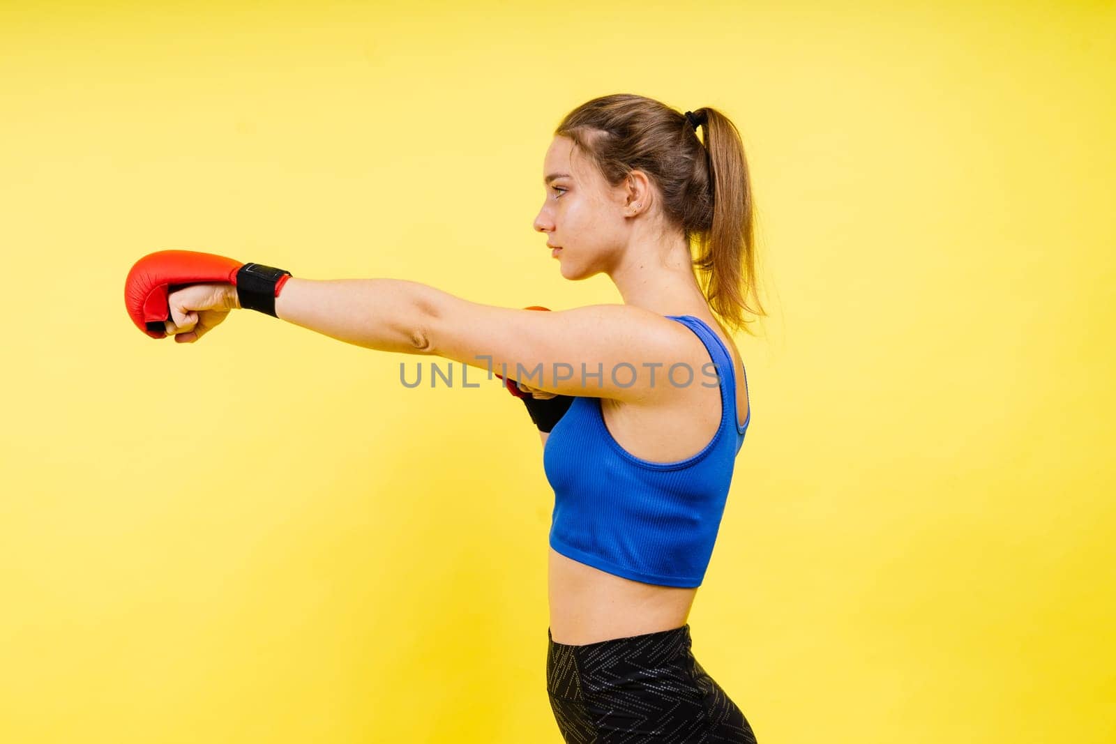 Woman boxer in gloves training on a grey and yellow background