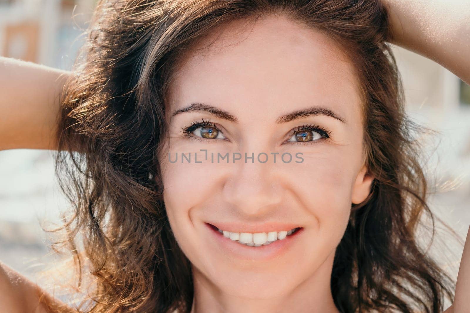 Woman travel portrait. Happy woman with long hair looking at camera and smiling. Close up portrait cute woman on a volcanic rock high above the sea by panophotograph