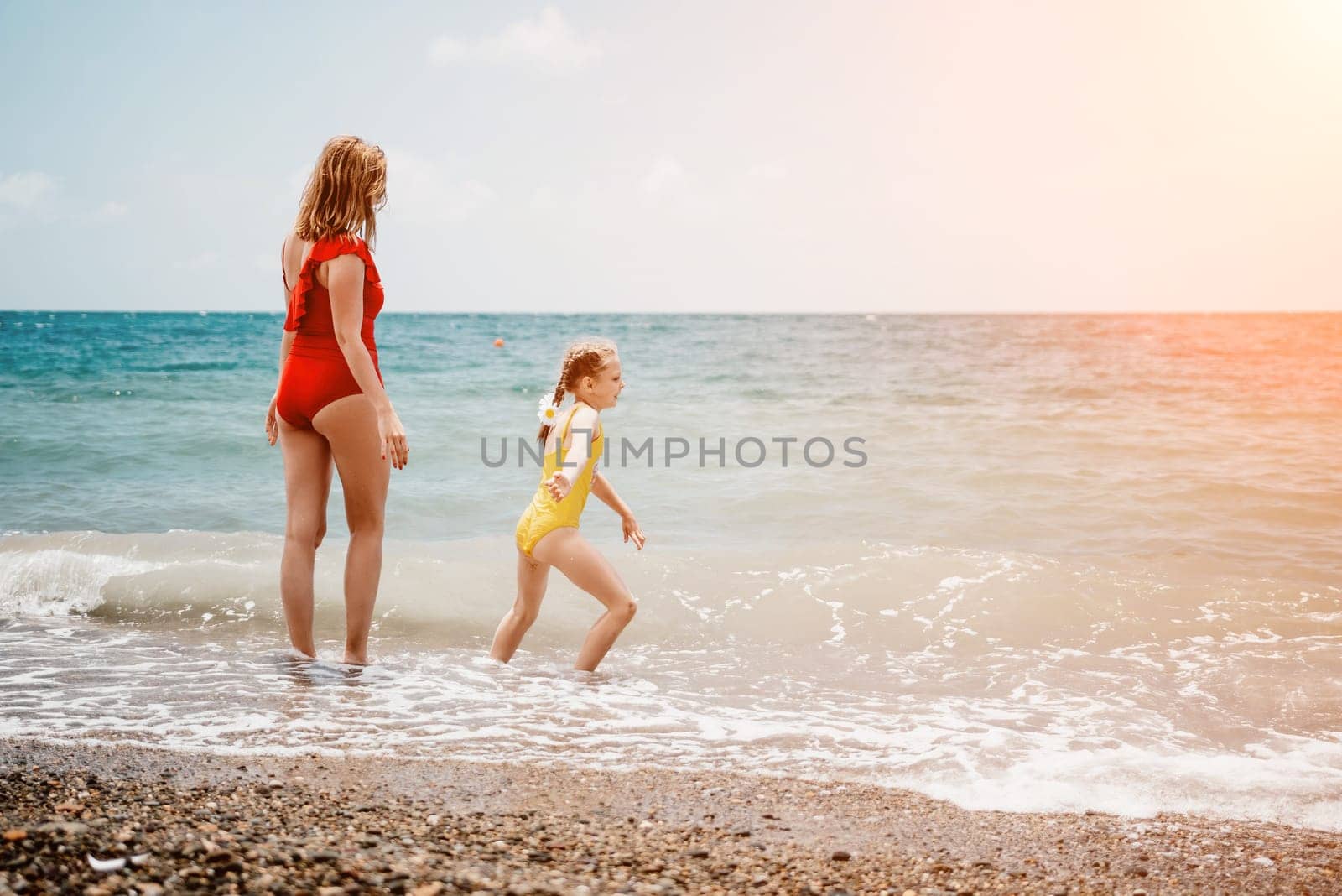 Happy loving family mother and daughter having fun together on the beach. Mum playing with her kid in holiday vacation next to the ocean - Family lifestyle and love concept.