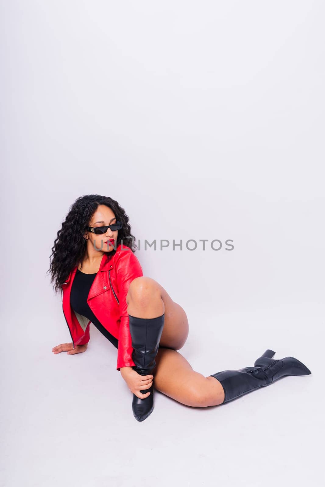 Sensual beautiful african ethnic woman in bodysuit posing in studio isolated red white background