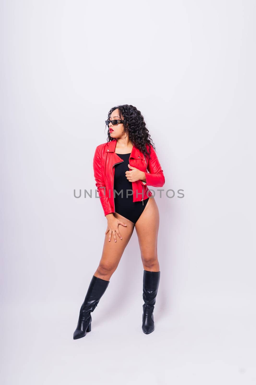 Sensual beautiful african ethnic woman in bodysuit posing in studio isolated red white background