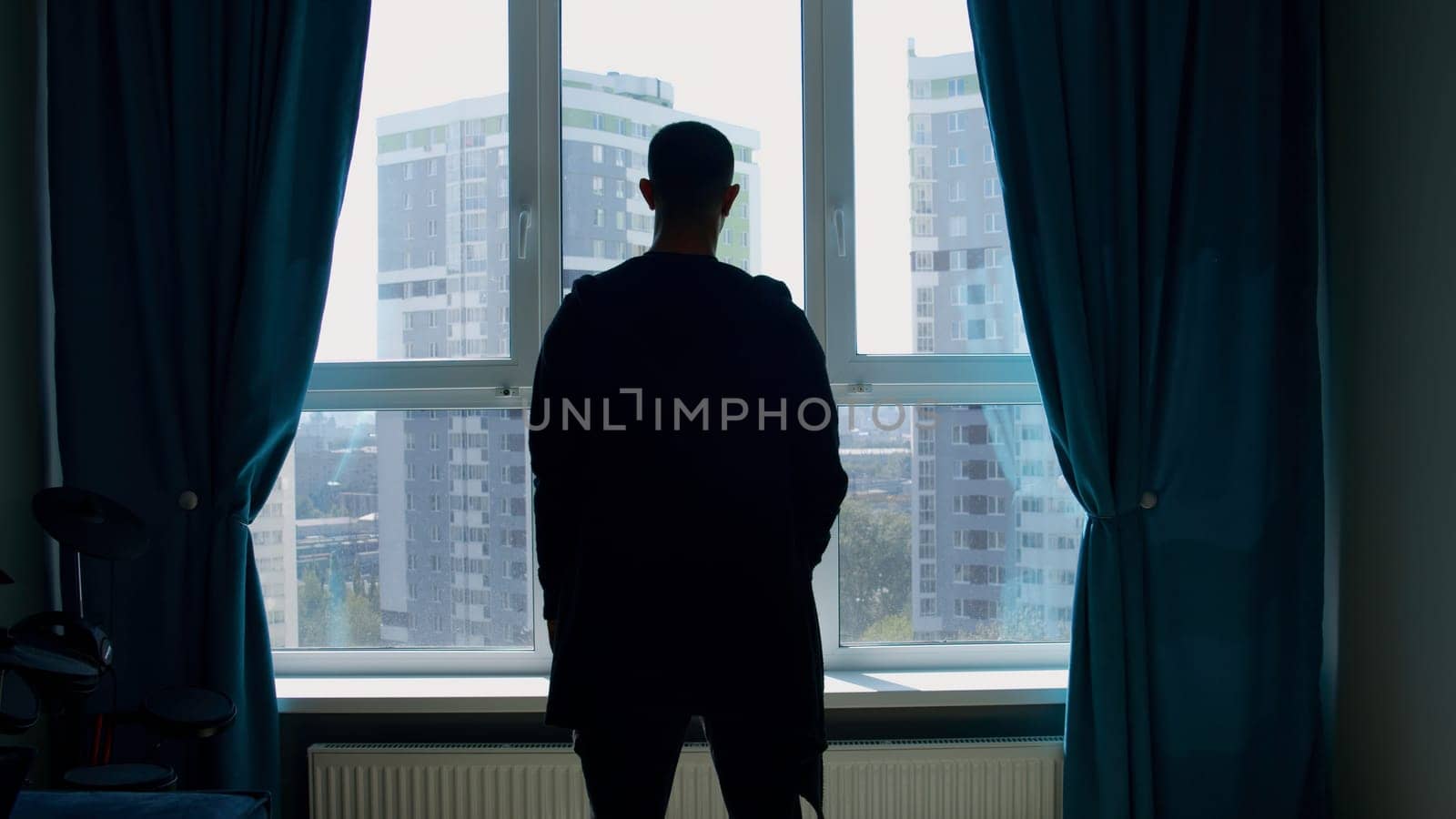 Men talking on the phone in the room. Media. Young silhouettes of men from the back in the apartment looking out the window into the distance. High quality 4k footage