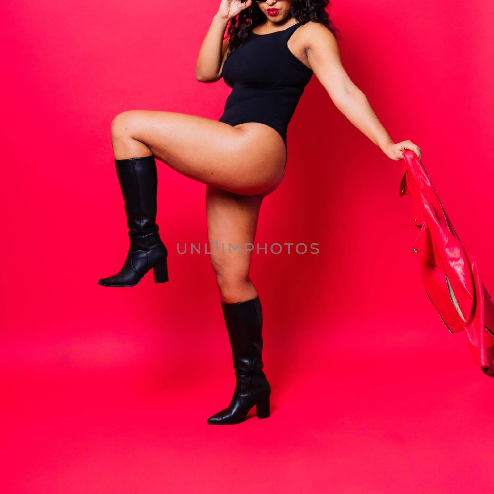 Sensual beautiful african ethnic woman in bodysuit posing in studio isolated on red white background by Zelenin