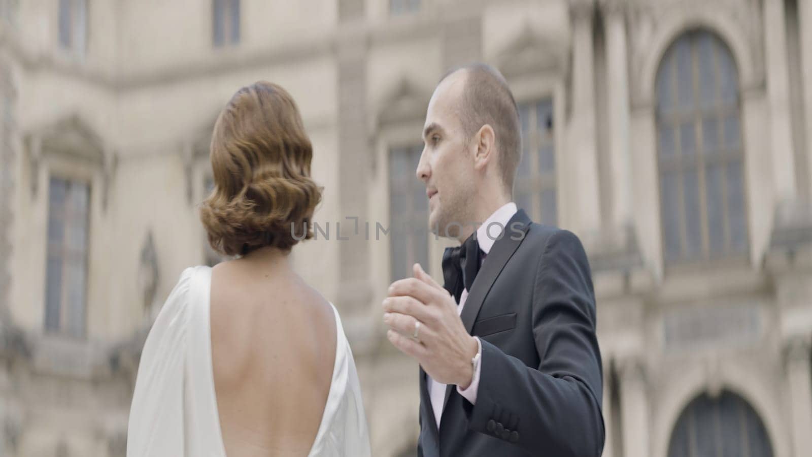 Dancing joyful couple. Action. A beautiful brunette in a white dress and her fiance are laughing and having fun in the square of a built-up city. High quality 4k footage