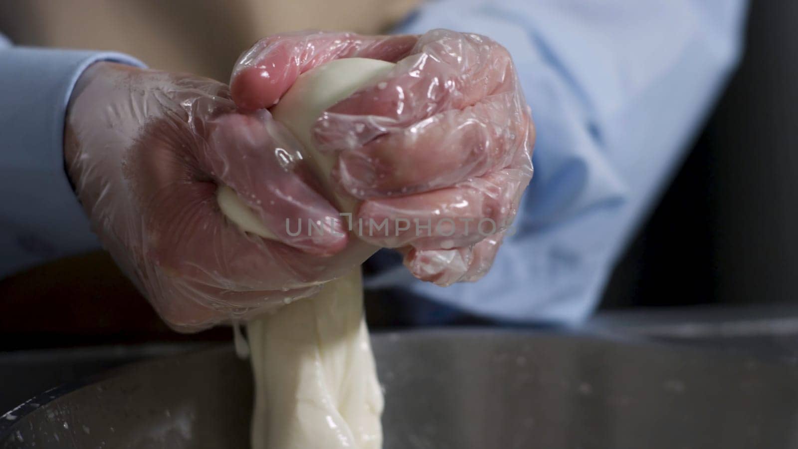 Close up for hands of a cheesemaker cutting mozzarella with hands, traditional food concept. Process of making delicious italian cheese.