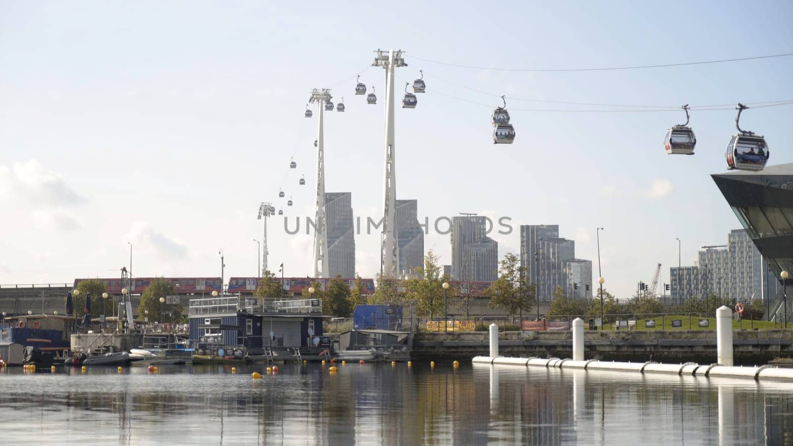 Beautiful view of promenade and modern city with cable car. Action. Beautiful panorama with cable car passing over canal on background of modern city.