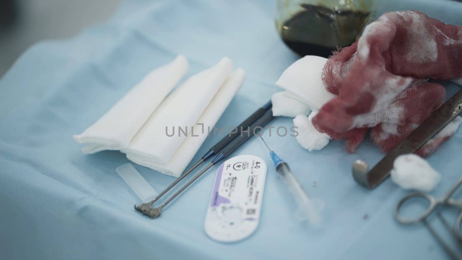 Surgical instruments and bloody bandages. Action. Close-up of surgical table with instruments and bloody bandages used during operation.