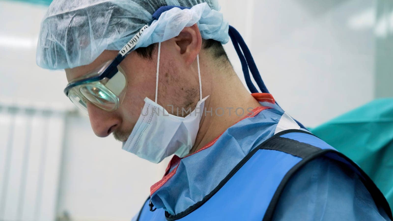 Close up of face of male doctor in a protective hat, glasses, and a medical mask. Creative. Medical worker during work at the hospital